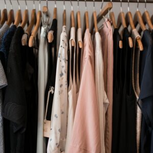 A stylish collection of women's clothing hanging on wooden hangers in a boutique setting.